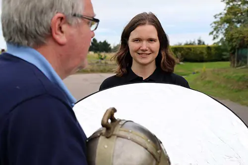 Sara holds a lighting disc up to lighten Cameron whilst filming